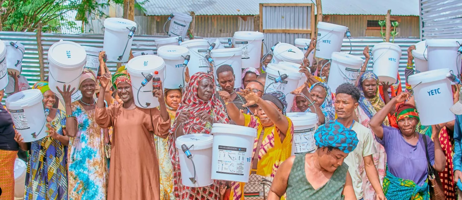 Community members holding up their new Safer Cleaner Water filtration buckets